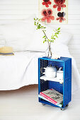 Side table made from blue plastic crate on castors