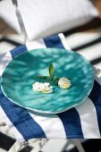White sprig of flowers on hand-made, turquoise dish