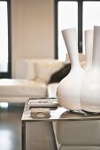 Designer vase with multiple necks on minimalist steel table, corner sofa in background