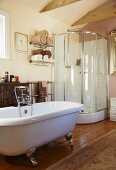 Freistehende Badewanne und moderne Duschkabine in einem Wohnbad mit Antikkommode und Orientteppich auf dem Dielenboden