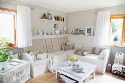 Gemütliche Wohnzimmerecke mit weiss lackiertem Couchtisch und Sitzbank in hellgrau getönter Zimmerecke mit Vintageflair