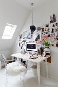 Ghoststuhl mit weißem Schaffell vor Schreibtisch und aufgeklebten Fotos an Wand, Dachschräge mit Dachflächenfenster