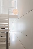 Fitted cupboards and white staircase in narrow foyer