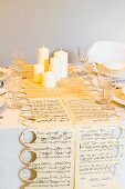 Table runner hand-made from sheet music, white pillar candles and crystal glasses