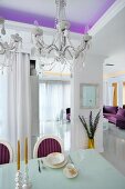 Elegant gedeckter Esstisch und Kristallkronleuchter in offenen weißen Designer-Wohnbereich