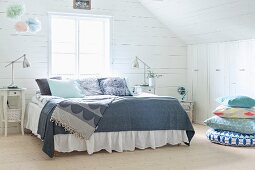 Double bed with grey patterned bedspreads in wood-clad attic room