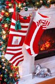 Knitted Christmas stockings hung on festively decorated mantelpiece
