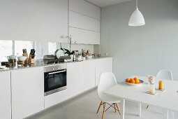 Essplatz mit Klassikermöbel in Weiß gegenüber moderne Küchenzeile am Fenster, mit integriertem Sichtschutz