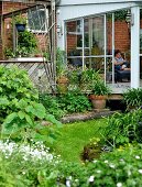 Blick von blühendem Garten auf Anbau mit Glasschiebetür