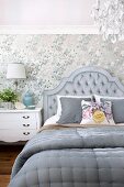 Double bed with grey upholstered headboard against patterned wallpaper in elegant bedroom