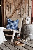 Easy chair with cushion on rustic board floor of veranda with wooden wall