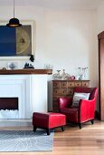 Red leather armchair with matching footstool next to open fireplace in corner of traditional room