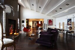 Offener Wohnraum in eklektizistischem Stil, modernes Sofa und teilweise sichtbarer Rokoko Sessel um offenem Kamin in einer Loftwohnung