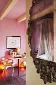 Baldachinbett spiegelt sich im Barock Spiegelrahmen, im Hintergrund moderner Tisch mit Stuhl im rosa Jugendzimmer