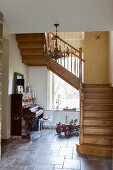 Holztreppe im gefliesten Hausflur mit antikem Klavier und nostalgischem Spielzeugauto