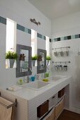 White washstand with twin sinks and mirrors between narrow windows in modern bathroom with tiled frieze