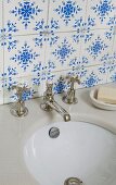 Traditional, blue and white tiles above stone washstand counter with old tap fittings and undermount sink