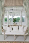 Delicate, antique bench with cane backrest in front of window element with view into conservatory
