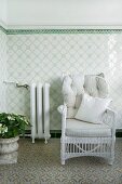 White wicker chair with pale, striped cushions against tiled dado in conservatory