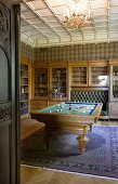 Old-fashioned room for convivial gatherings with glass-fronted cabinets, integrated leather bench, library and billiard table