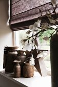 Keramikvasen in verschiedenen Grössen auf Fensterbank, im Vordergrund Ausschnitt einer Vase mit Blütenzweig