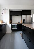 Free-standing counter in kitchen with black fitted cupboards
