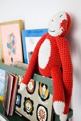 Crocheted toy monkey and books on shelf