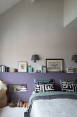 Modernes Schlafzimmer mit mauvefarbenem Bettkopfteil, Bücherstapel, schwarz-weißen Kissenbezügen und Vintage-Schneiderpuppe
