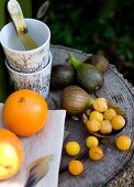 Frisches Obst und Becherstapel auf Baumstamm-Tisch im Freien