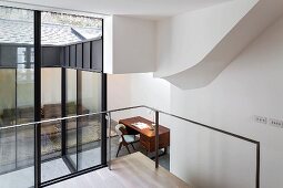 Blick durch Verglasung auf Wohnzimmer mit Sofa und Schreibtisch im Anbau