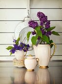 Edles Kaffeegeschirr dekoriert mit Blüten vor Vintage Küchensieb