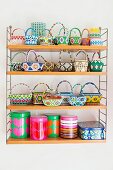 Collection of colourful beaded baskets and printed tins on wall-mounted String shelves