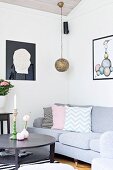 Black round coffee table, grey sofa and pendant lamp with spherical metal lampshade