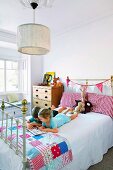 Lesende Kinder auf romantischem Bett mit Patchworkdecke in Mädchenzimmer mit nostalgischem Flair
