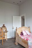 Carved child's bed with high headboard in renovated child's bedroom