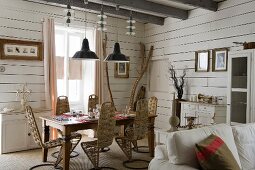 Gebogene Designerstühle mit Geflecht um gedeckten Esstisch in Zimmerecke mit weisser Holzverschalung an Wand