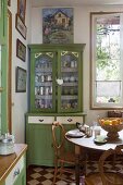 Green dresser and wooden dining table in traditional kitchen