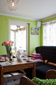 Holztisch mit Kaffeegeschirr und Pfingstrosen im Wohnzimmer, mit lindgrüner Wand