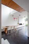 weiße Stühle um Holztisch auf poliertem Betonboden in modernem Wohnraum