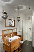 Oriental pendant lamps above custom-made washstand with lid and floor-level shower in background
