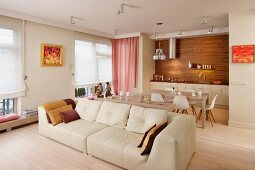 Wood and pink accents in cream living-dining room with large sofa and classic chairs in background