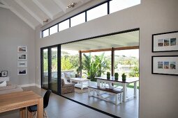 Blick von Wohnbereich auf Terrasse mit Esstisch und Lounge