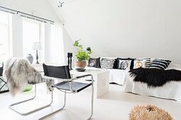 Freischwinger mit schwarzem Lederbezug und Sofa mit Kissen in Loungeecke im Dachzimmer