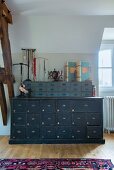 Blue-grey vintage chest of drawers with smaller set of drawers on top, jewellery stands and vintage folders in attic room