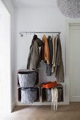 Coats hanging from open coat rack above felt baskets in wooden crates