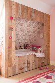 Cubby bed made from reclaimed boards in girl's bedroom with sloping ceiling
