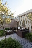 Trees in large planters and modern, dark wicker outdoor furniture on wooden terrace