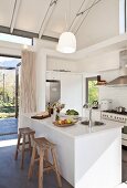 White open-plan kitchen with island counter and exposed beams in open roof area