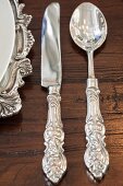 Antique silver knife, spoon and charger plate on wooden table