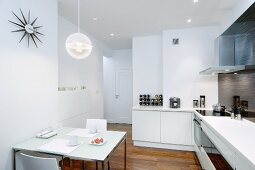 Dining table with breakfast place settings in open-plan, white, modern kitchen